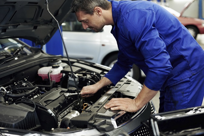 Accomplished mechanic tightening a sparkplug into place during a service at his workshop